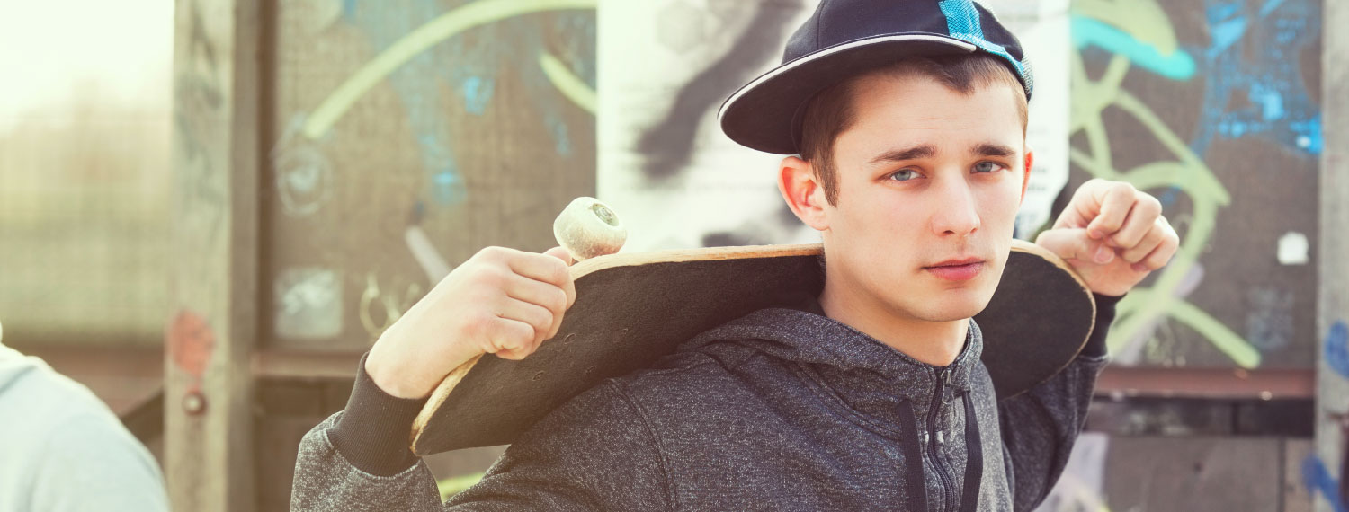 Junge mit Basketballkappe und Skateboard.