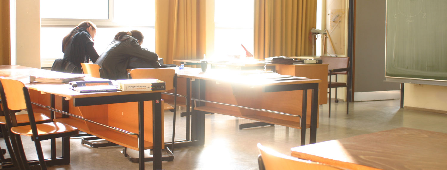 Zwei junge Menschen sitzen in einem Klassenzimmer.