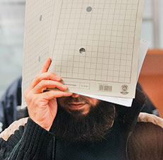 Foto: Ein Mann verdeckt sein Gesicht mit einem Aktendeckel.