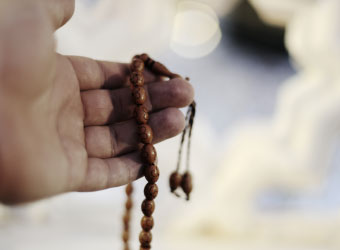 Hand hält Gebetsketten.