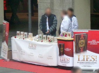Drei Männer an einem salafistischen „LIES“-Stand.