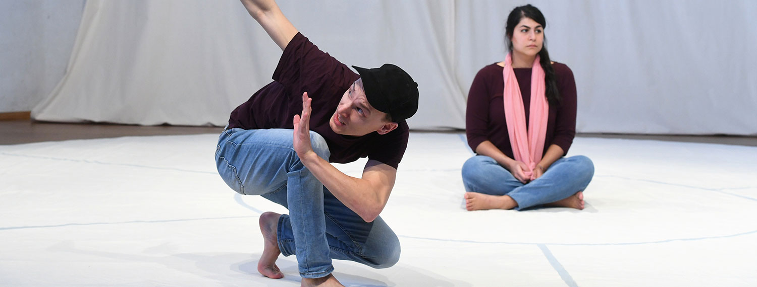 Ein Mann und eine Frau bei einer Performance in einer Turnhalle.